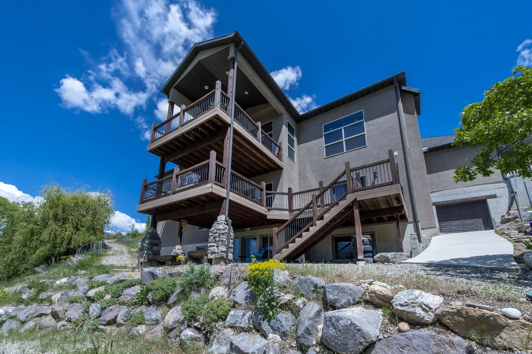 Multi-level decks with wood railings, exterior stairs, stucco siding, and an integrated garage