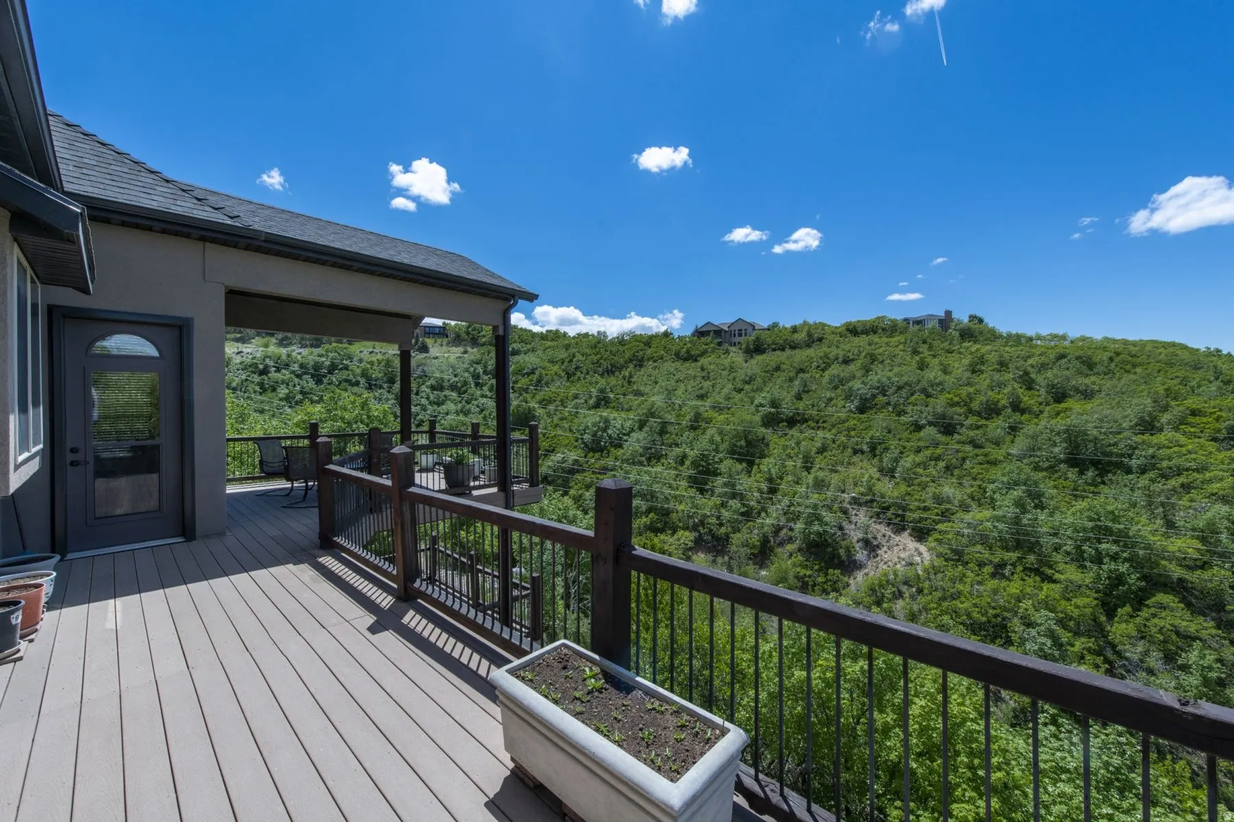 Expansive outdoor deck with composite decking, featuring a dark wood-finish railing and a covered portion