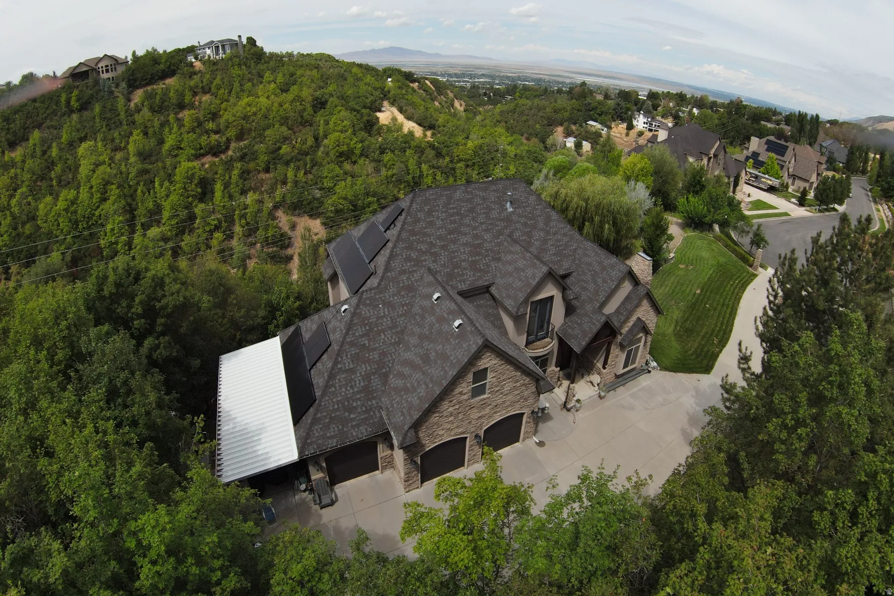 Exterior featuring a stone and siding facade, multi-gabled roofline, solar panels, and an attached three-car garage