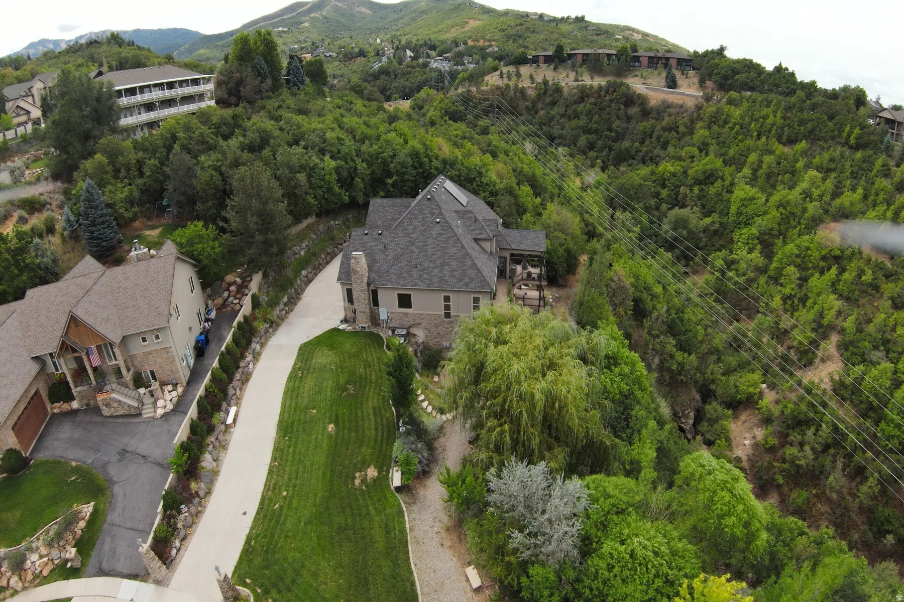 Stone and stucco exterior with a multi-level roofline, prominent chimney, and an attached deck