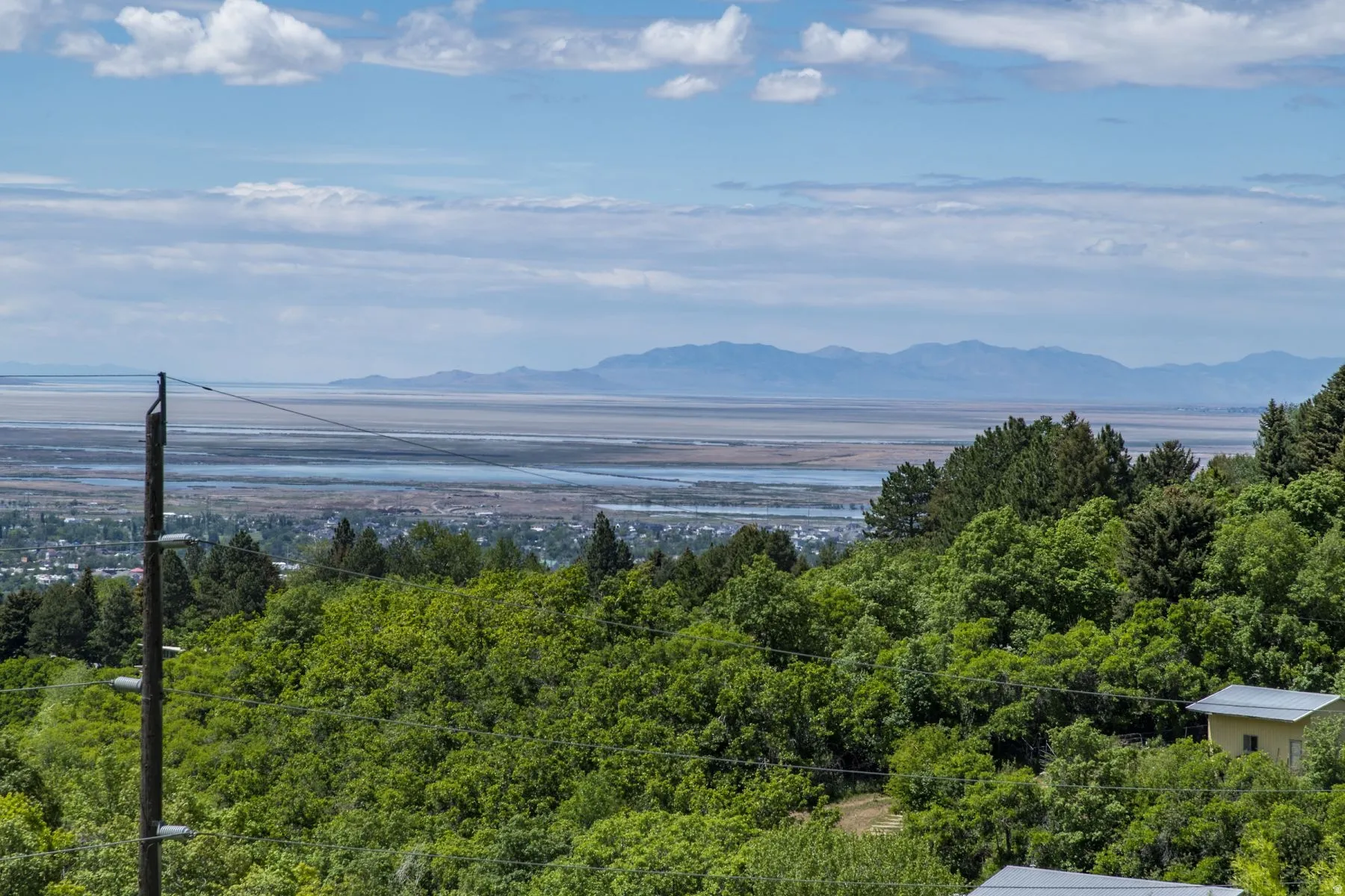 Expansive scenery featuring distant mountains, a large body of water, and a cityscape nestled among lush greenery
