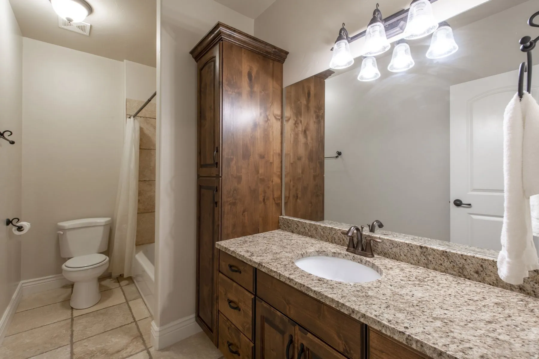 Bathroom featuring a vanity with a granite countertop, undermount sink, and wood-finish cabinetry