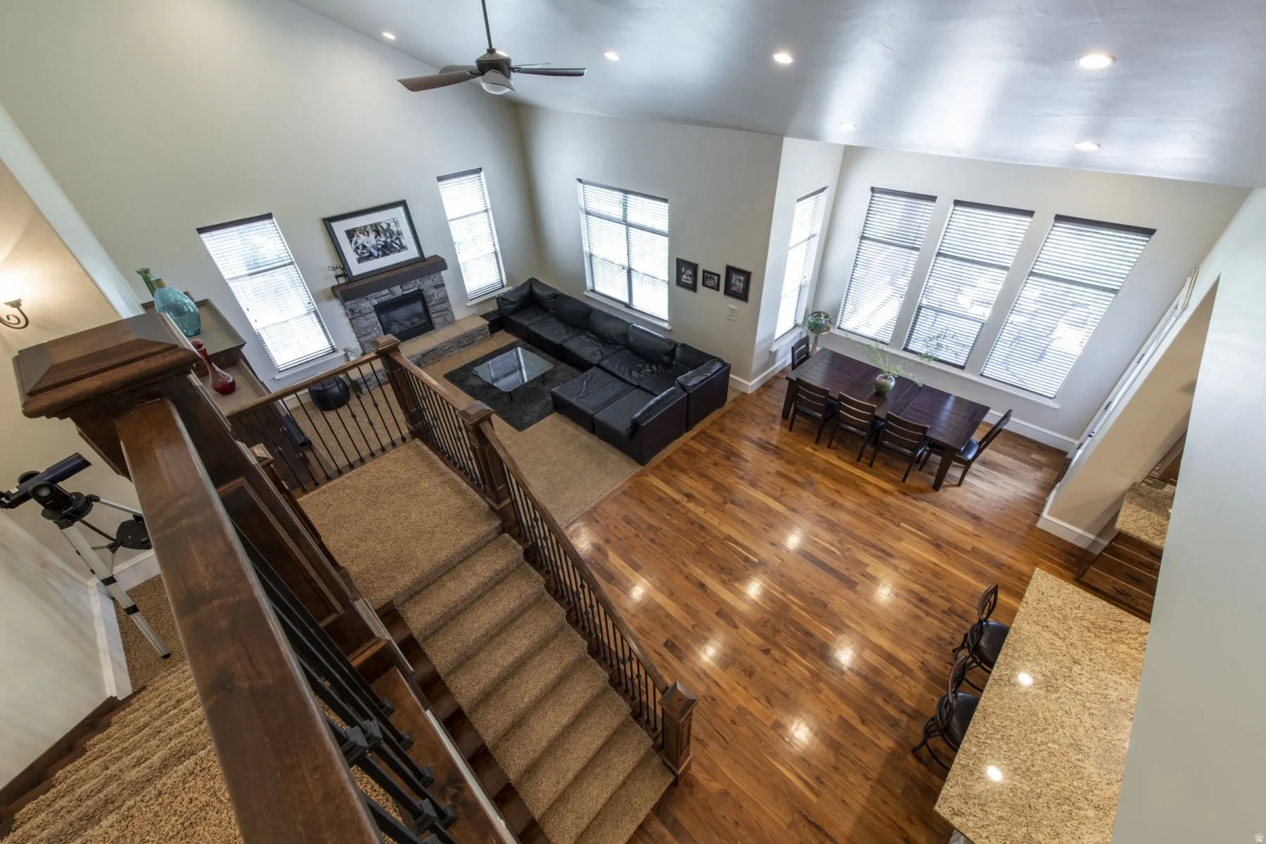 Vaulted ceilings with recessed lighting, wood-finish flooring, stone fireplace, and large windows