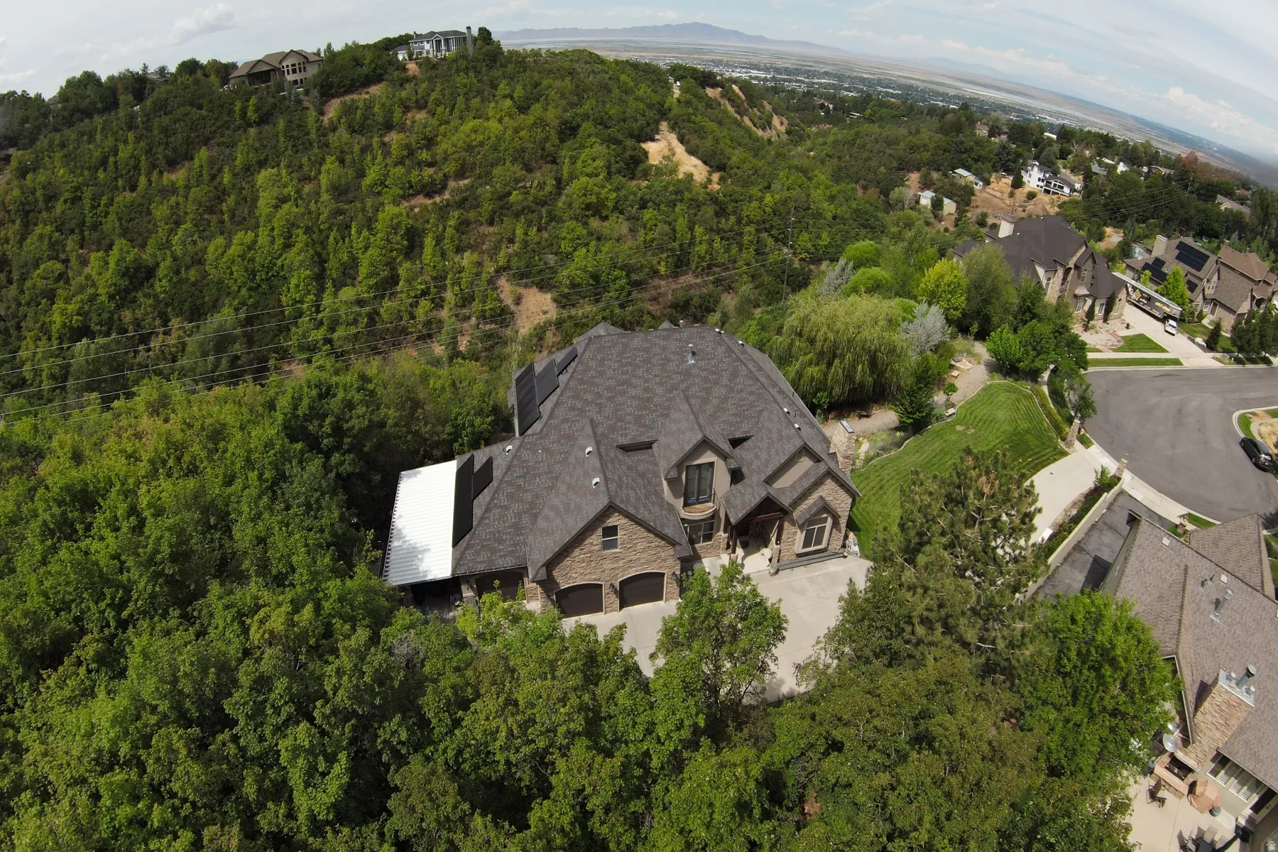 Stone veneer exterior with a dark shingle roof, integrated two-car garage, and a concrete driveway
