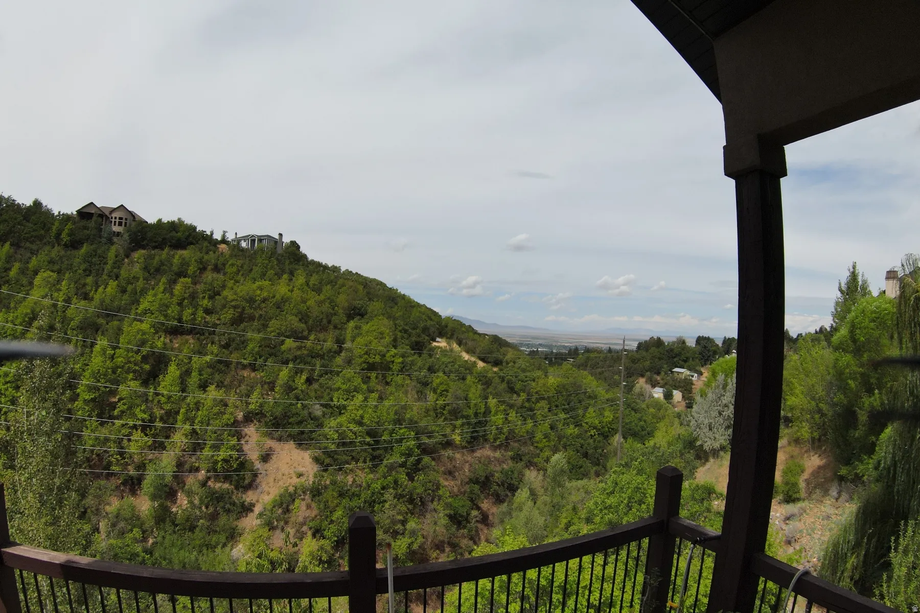 Balcony with wood railing, offering a expansive natural landscape and distant cityscape