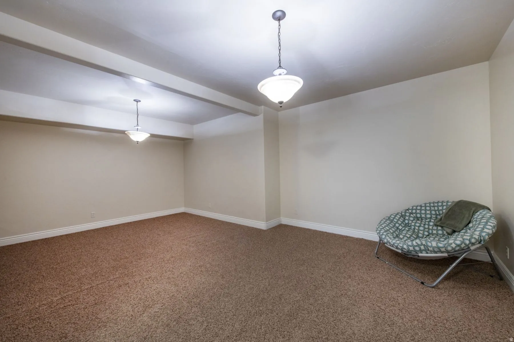 Recessed lighting with decorative pendant fixtures, neutral wall tones, and plush carpeting