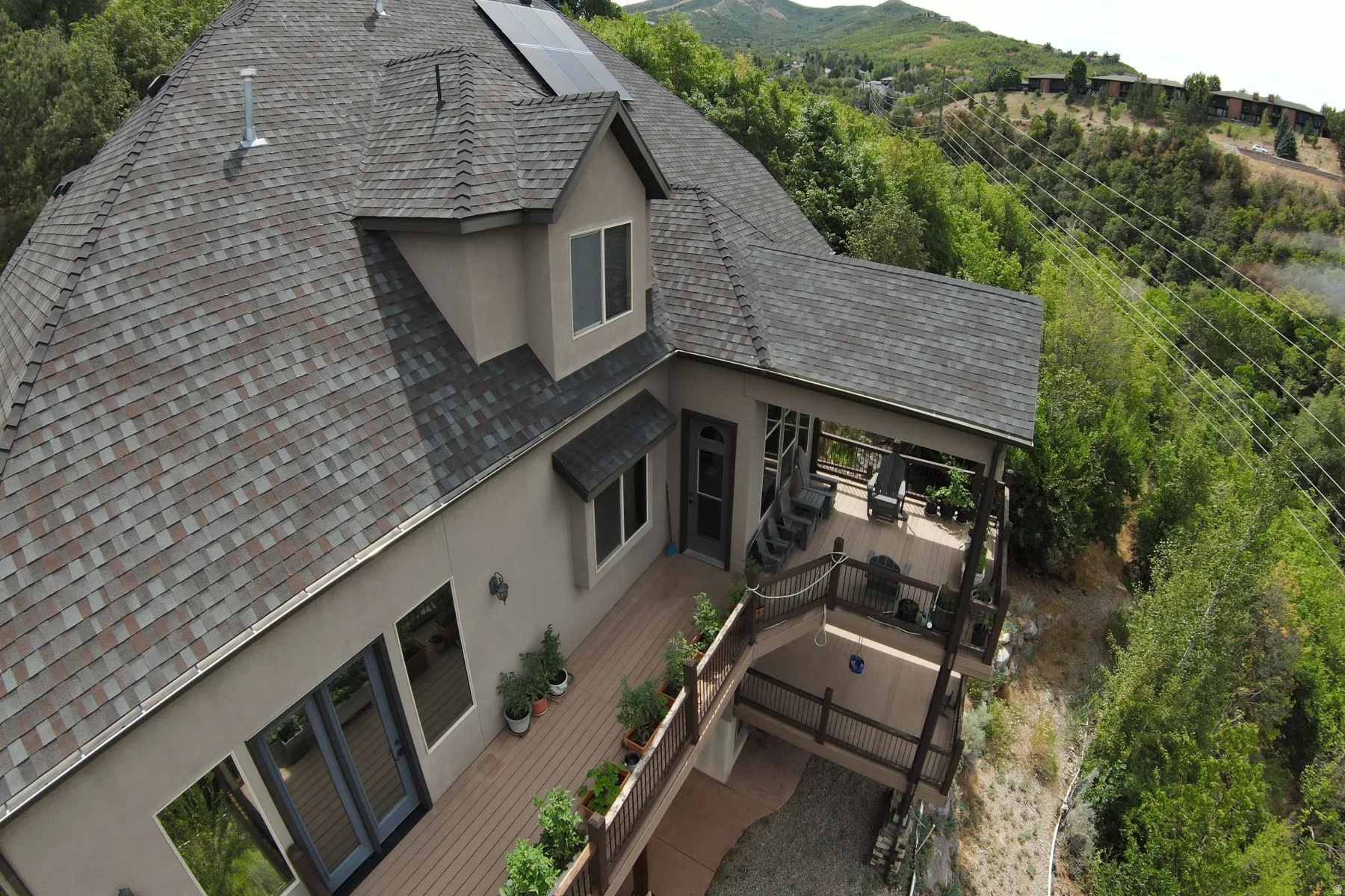 Multi-level outdoor decking with wood-finish surfaces, covered patio, and exterior lighting
