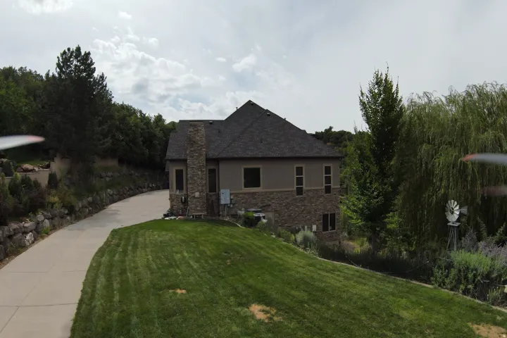 Two-story residence featuring a stone and stucco exterior, a dark shingle roof, a stone chimney, and multiple windows