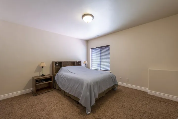Carpeted bedroom featuring neutral wall tones and a window with blinds