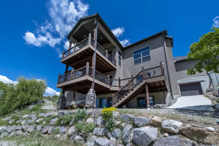 Multi-level decks with wood railings, exterior stairs, stucco siding, and an integrated garage