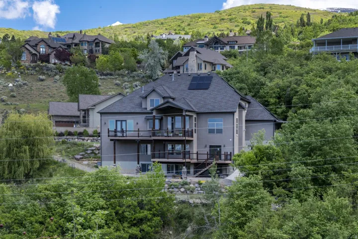 Multi-level residence with a dark shingle roof, solar panels, and multiple balconies