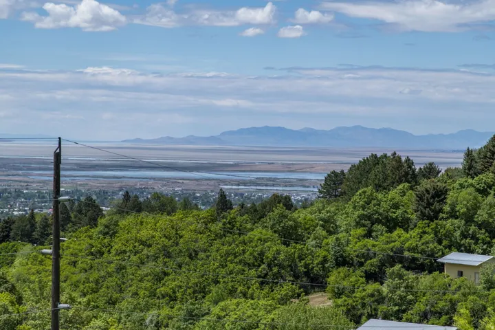 Expansive scenery featuring distant mountains, a large body of water, and a cityscape nestled among lush greenery