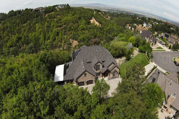 Stone veneer exterior with a dark shingle roof, integrated two-car garage, and a concrete driveway