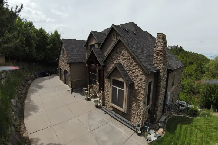 Stone and stucco exterior with dark shingle roofing