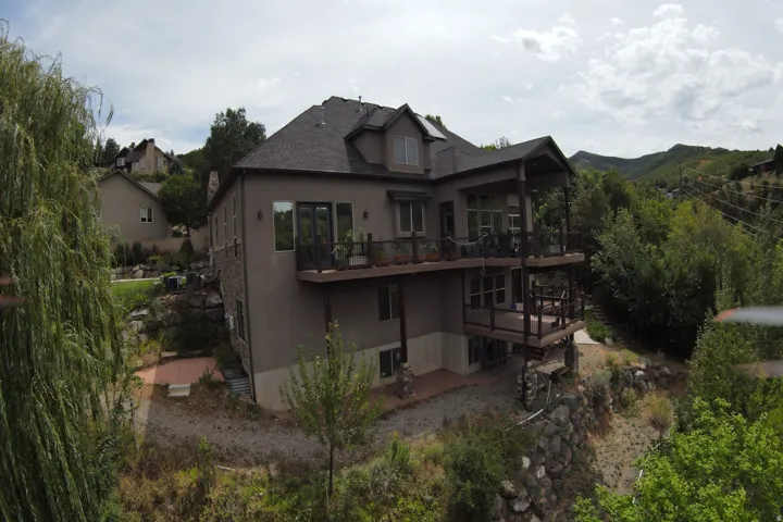 Multi-level residence featuring a stone and stucco exterior, covered upper and lower deck spaces, and a gabled roofline