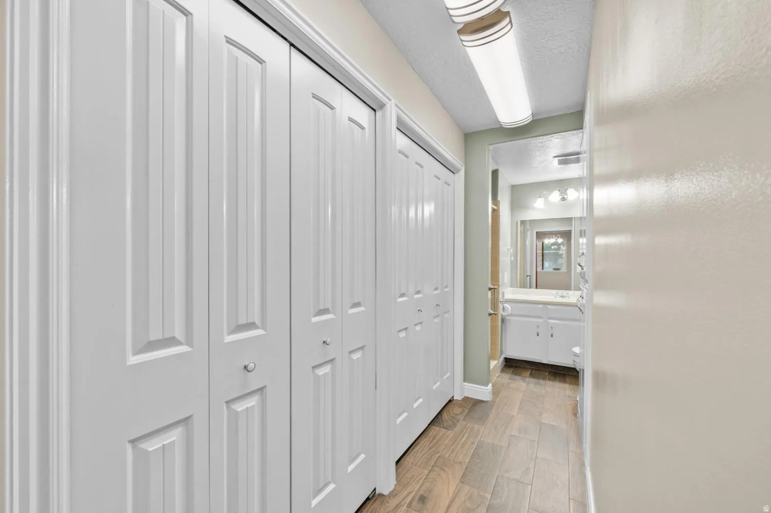 Hallway with wood-finish flooring and multiple paneled bi-fold closet doors