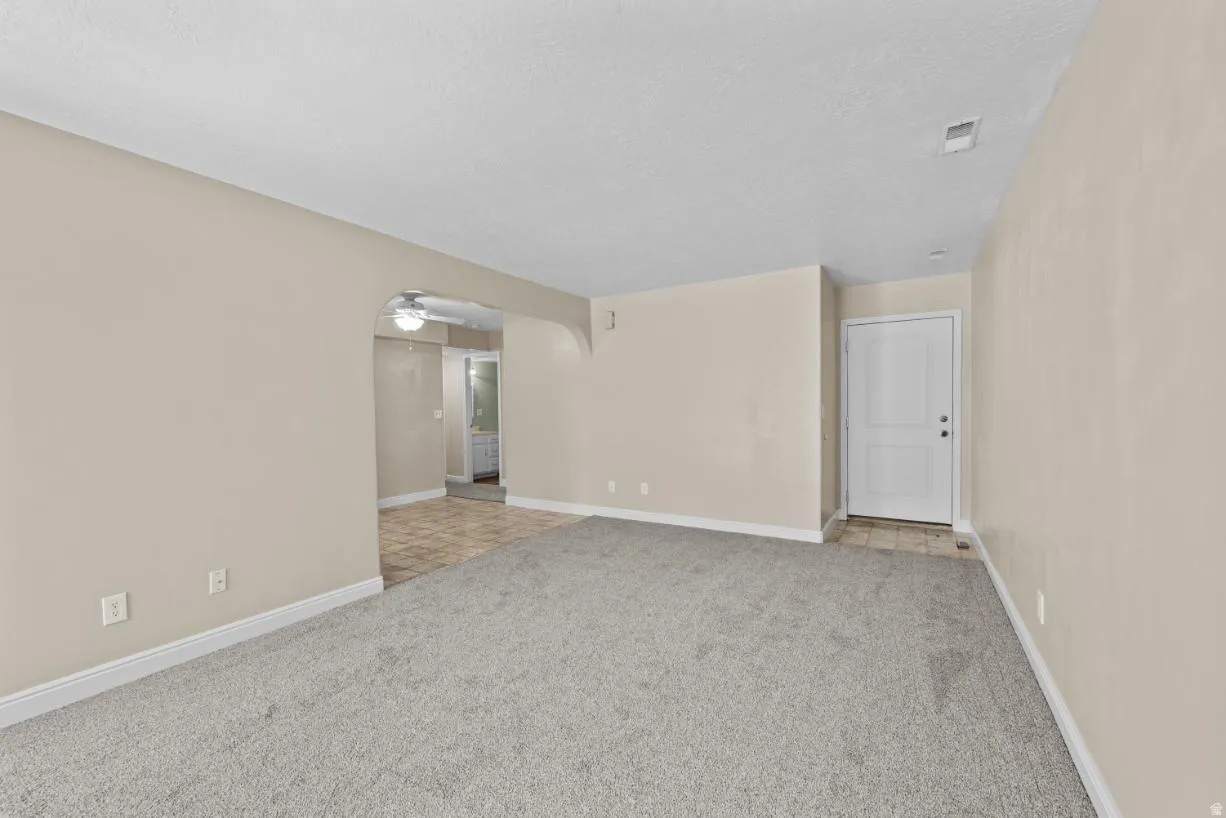 Spacious interior featuring neutral wall tones, gray carpeting, and an arched doorway