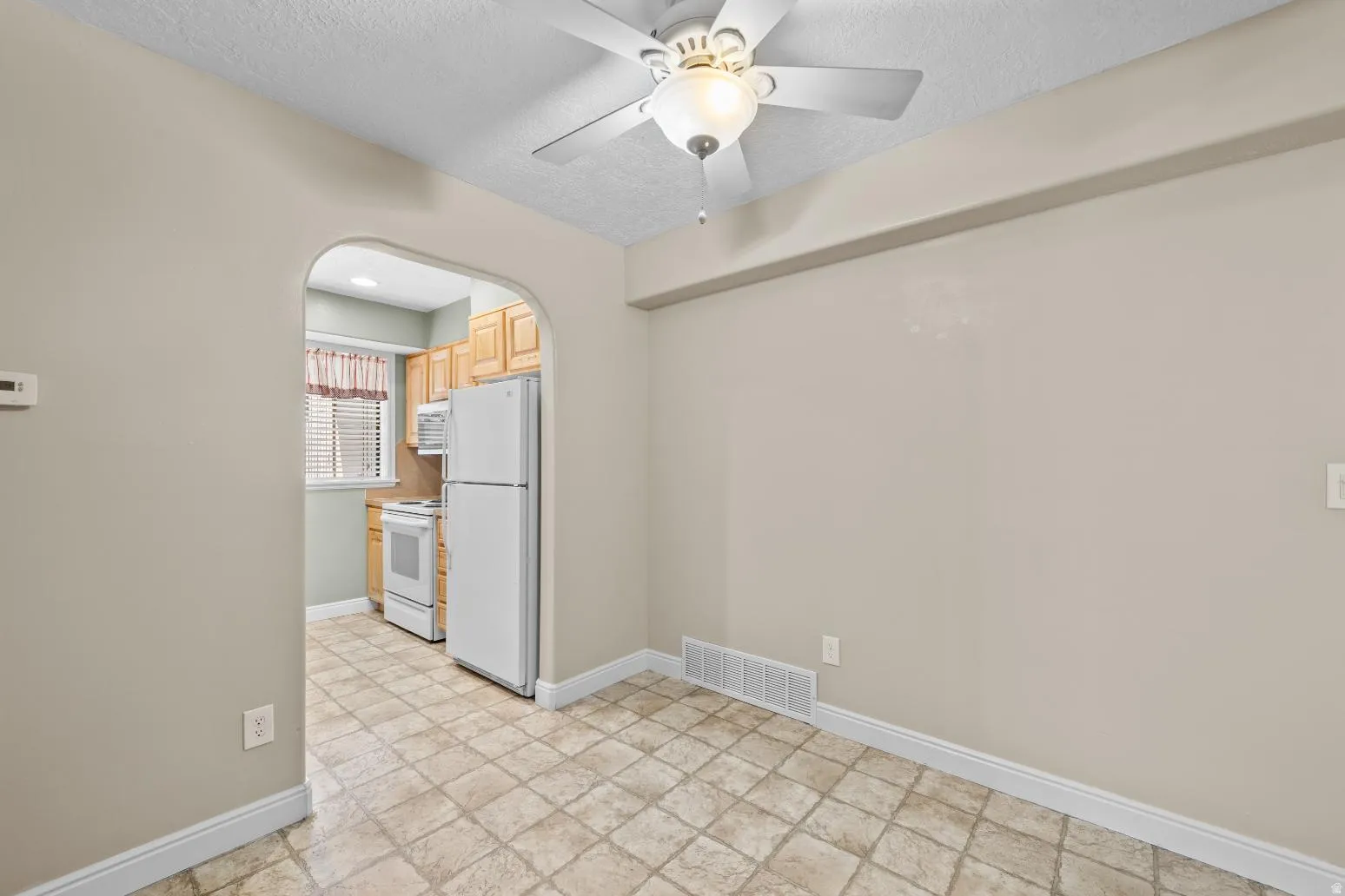 Arched doorway with tile flooring and a ceiling fan