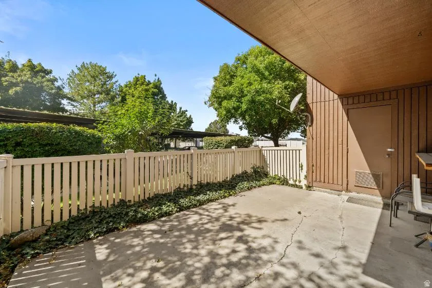 Private patio with concrete flooring, framed by a white picket fence, and a secure storage door