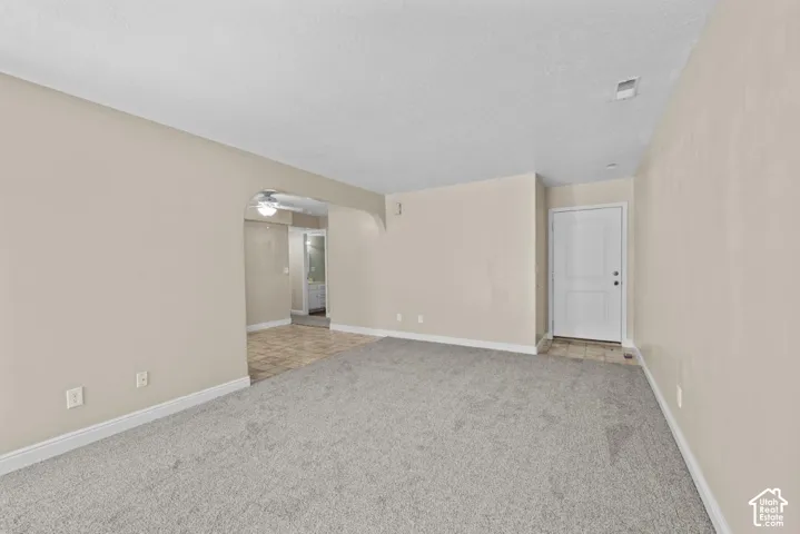 Spacious interior featuring neutral wall tones, gray carpeting, and an arched doorway