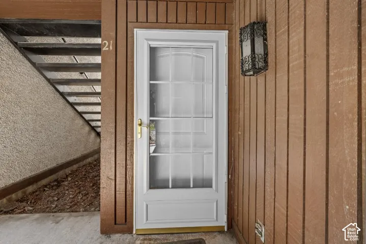 White entry door with grid-pane glass and brass hardware, complemented by a decorative wall-mounted sconce
