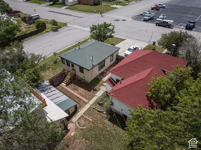 Exterior featuring a green metal roof, light-colored siding, and a wooden deck with stairs