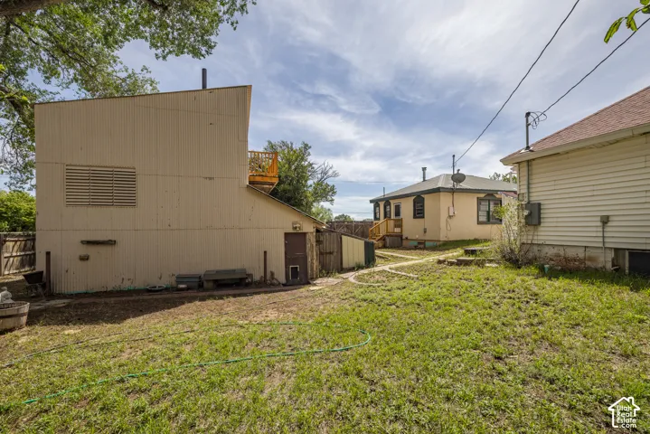 Rear exterior with a corrugated metal facade, a wooden deck, and a fenced perimeter