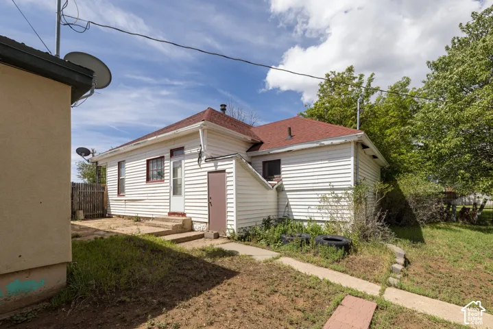 Red-pitched roof, white horizontal siding, concrete steps, and a privacy fence