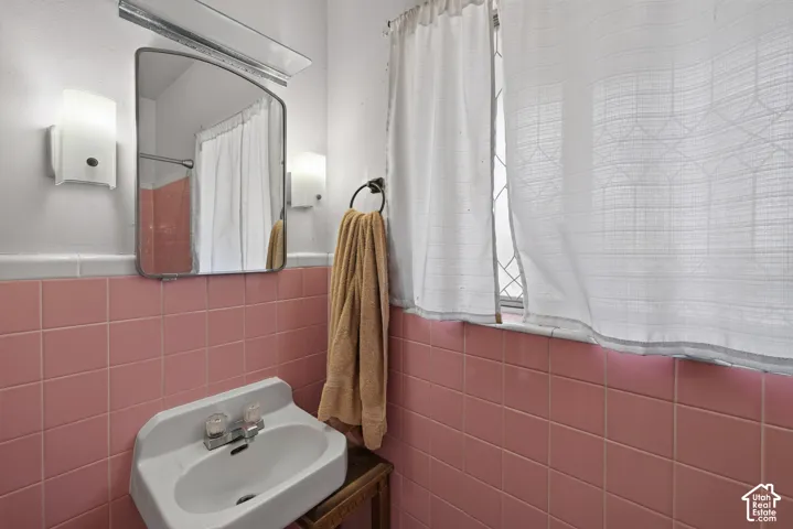 Pink tile wainscoting with white trim, built-in wall sconces, and a window with a security screen