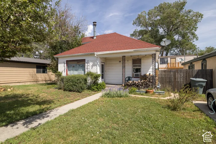 White siding exterior featuring a red shingle roof and a concrete walkway