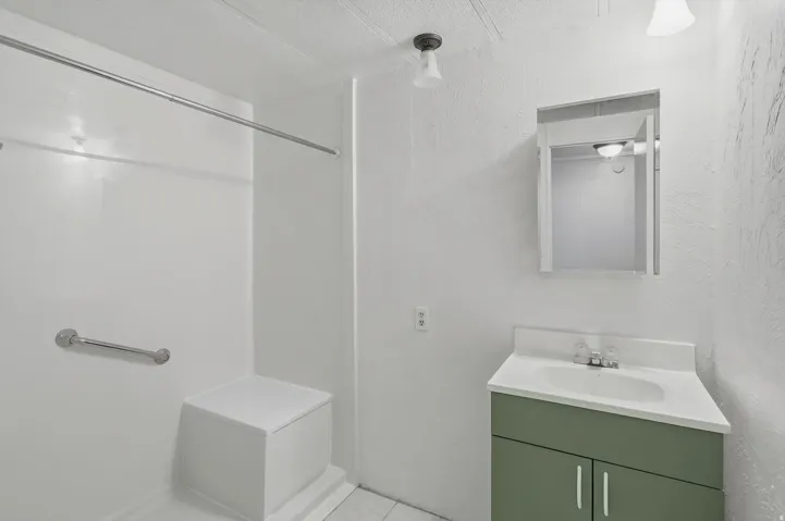 Step-in shower with grab bar and integrated seating