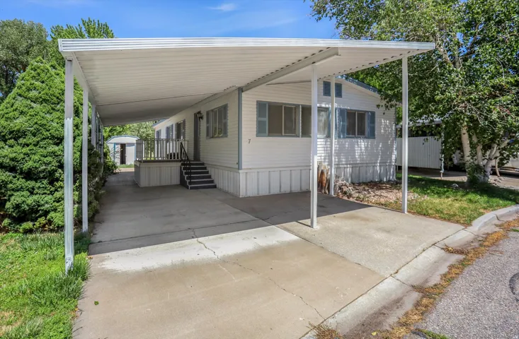White siding exterior with a covered carport, concrete driveway, and front entry stairs