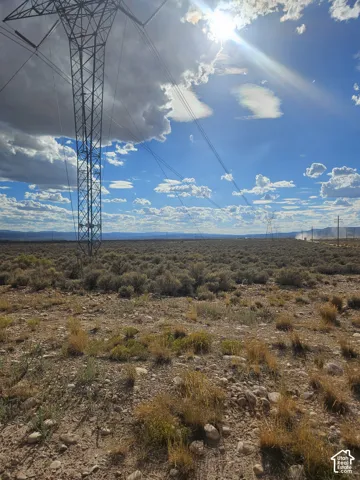 Expansive open land featuring natural vegetation and distant mountains