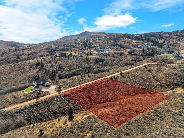Expansive land parcel with surrounding natural vegetation and distant residential structures