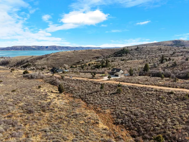 Expansive natural terrain, distant body of water, and a single-family residence with an attached garage
