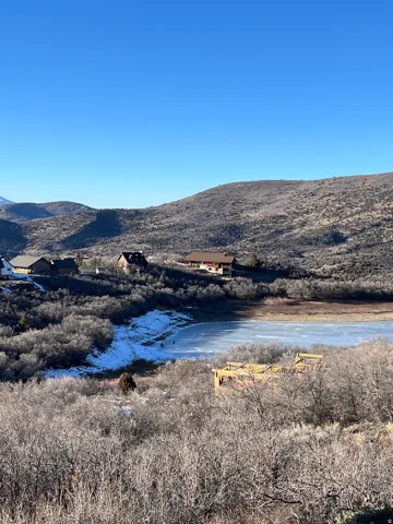 Hillside property featuring natural landscaping, a partially constructed building, and distant structures
