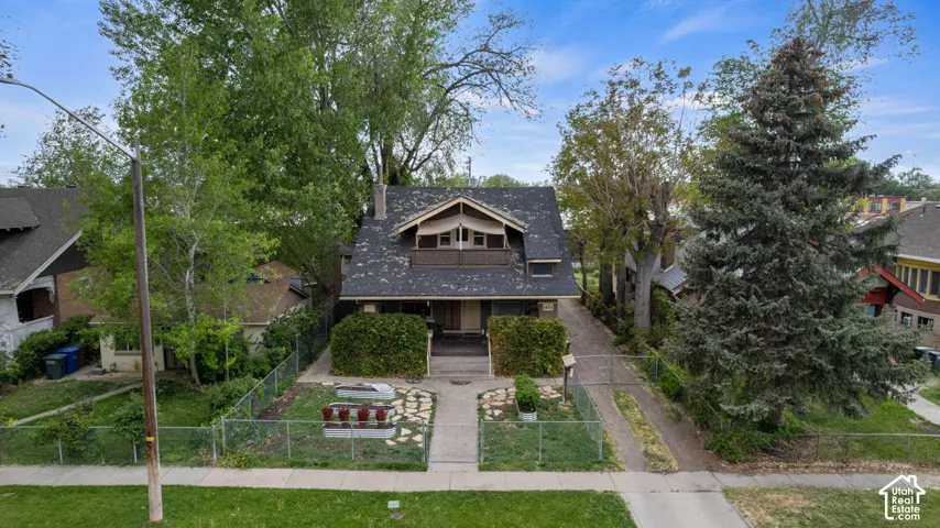 Gable roofline with exposed eaves, front balcony, covered entry, front walkway with stepping stones, and mature trees