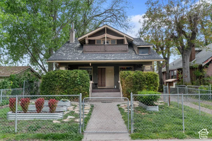 Craftsman-style exterior featuring a covered porch, upper-level balcony, and a prominent chimney
