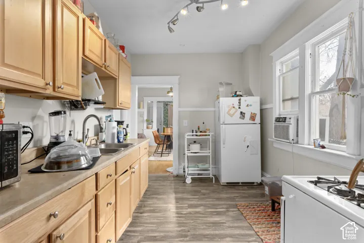 Galley kitchen featuring natural wood cabinetry with hardware accents, stainless steel appliances including a gas range, laminate countertops, and track lighting