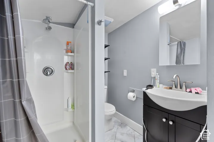 Bathroom featuring a black vanity with a white sink, wall-mounted mirror, and a shower with a chrome fixture