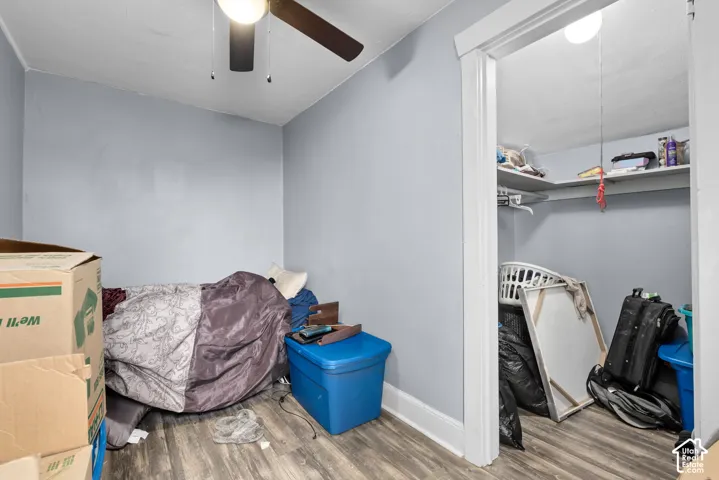 Wood-finish flooring, ceiling fan with integrated lighting, and a closet with built-in shelving