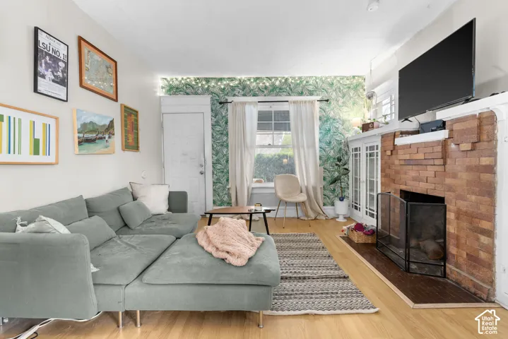 Hardwood flooring, brick fireplace with a white mantel, built-in cabinetry, and window with natural light