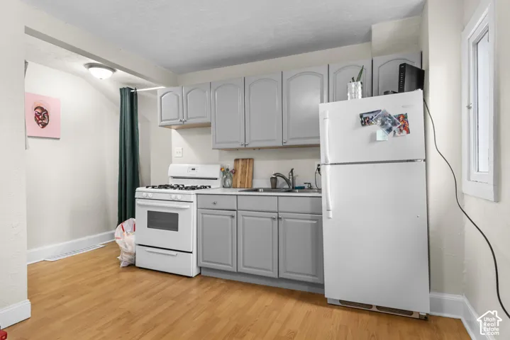 Kitchen featuring wood-finish flooring, light grey cabinetry, white countertops, and a full-size white refrigerator