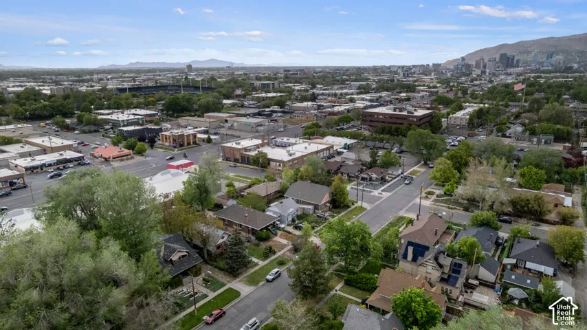 Urban landscape featuring a mix of residential and commercial structures, an established street grid, and mature trees