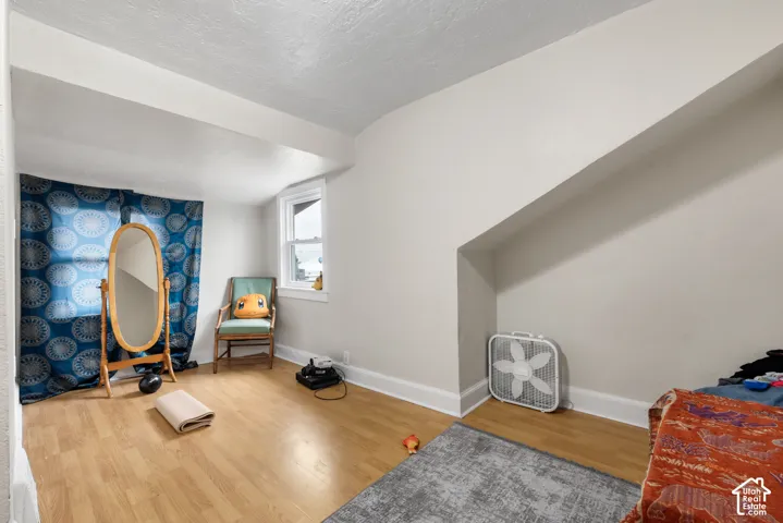 Recessed window with white trim, wood-finish flooring, and sloped ceiling