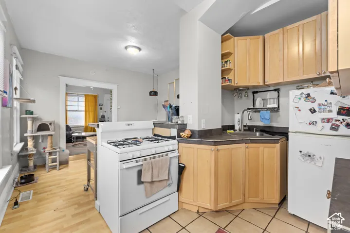 Light wood-finish flooring, white gas range, and wood cabinets