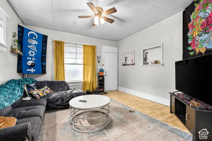 Paneled ceiling, light-toned walls, wood-finish flooring, and a ceiling fan with integrated lighting