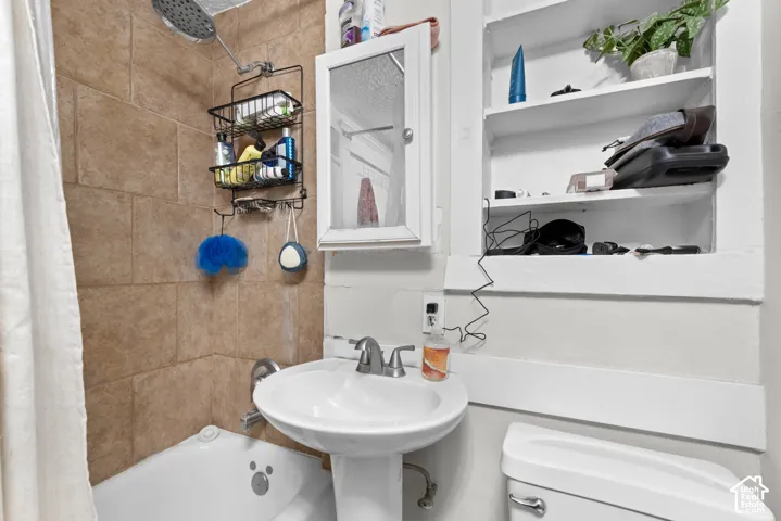 Pedestal sink, wall-mounted medicine cabinet, built-in recessed shelving, tiled shower surround, and a white toilet