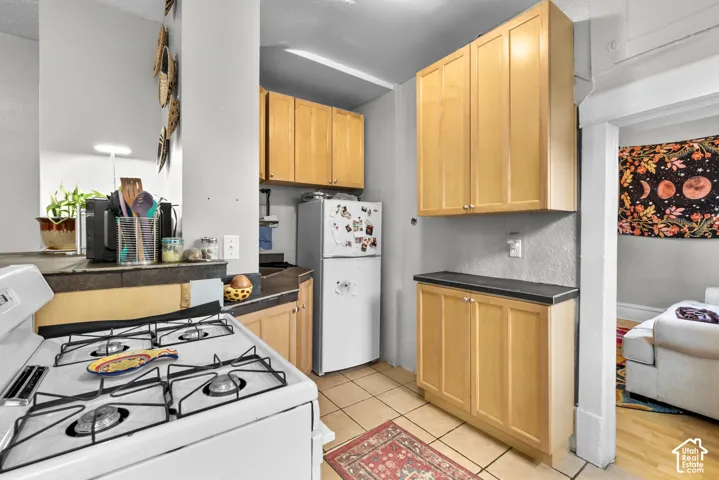Kitchen with wood-finish cabinetry, dark countertops, and tile flooring