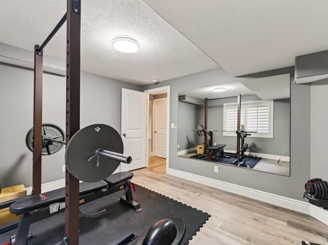 Wood-finish flooring, full-wall mirror, window with plantation shutters, recessed ceiling lighting, and white baseboards